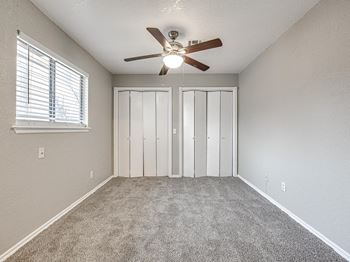 An empty bedroom with a ceiling fan and a window